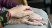 En ung hand som ligger över en äldre hand.